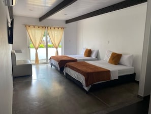 A hotel room with two beds, a small seating area, and a window with curtains. - Hotel Campestre Serrania de Manacacias (SAN MARTÍN)