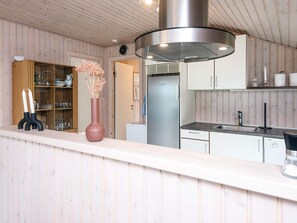 A modern kitchen with wooden paneling, a stainless steel range hood, and a white countertop. - 6 Person Holiday Home in Juelsminde (Horsens)