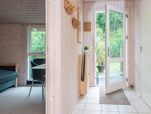 A room with a bed, a chair, a wooden door, and a view of greenery outside. - 6 Person Holiday Home in Juelsminde (Horsens)