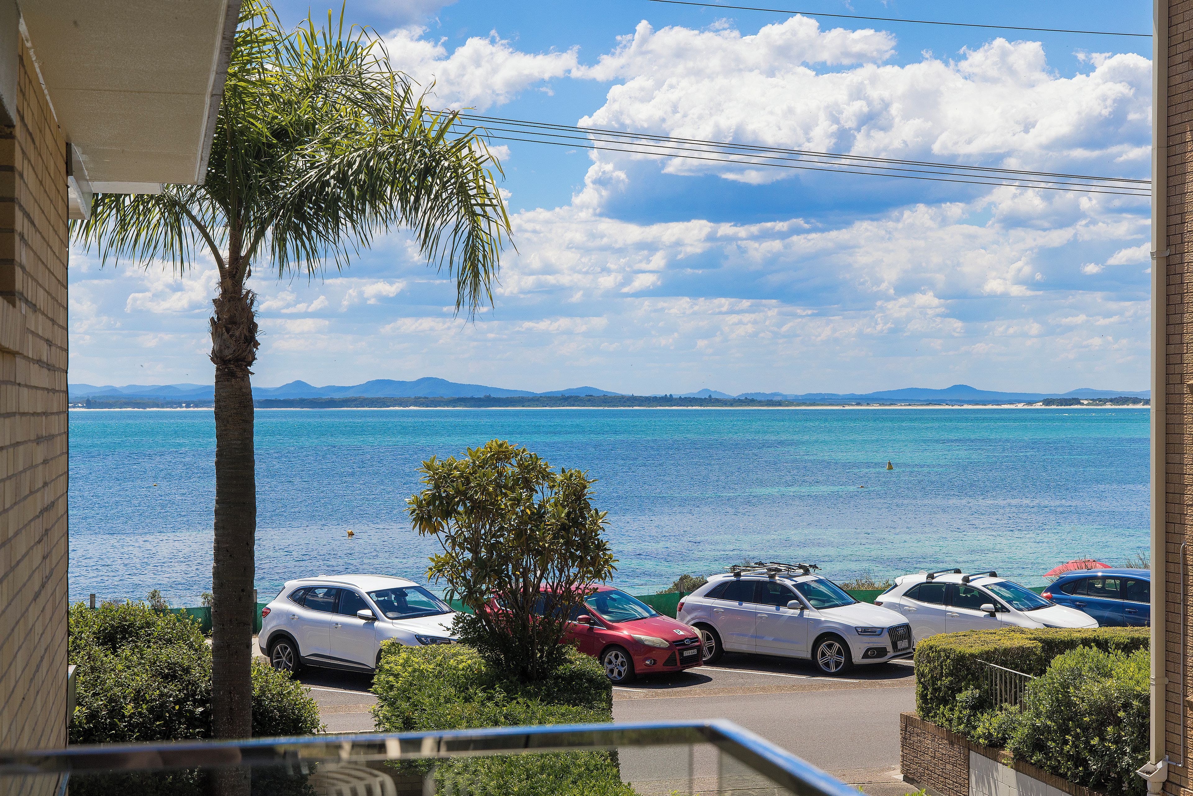 Une vue sur la côte, avec des voitures garées et un ciel dégagé.