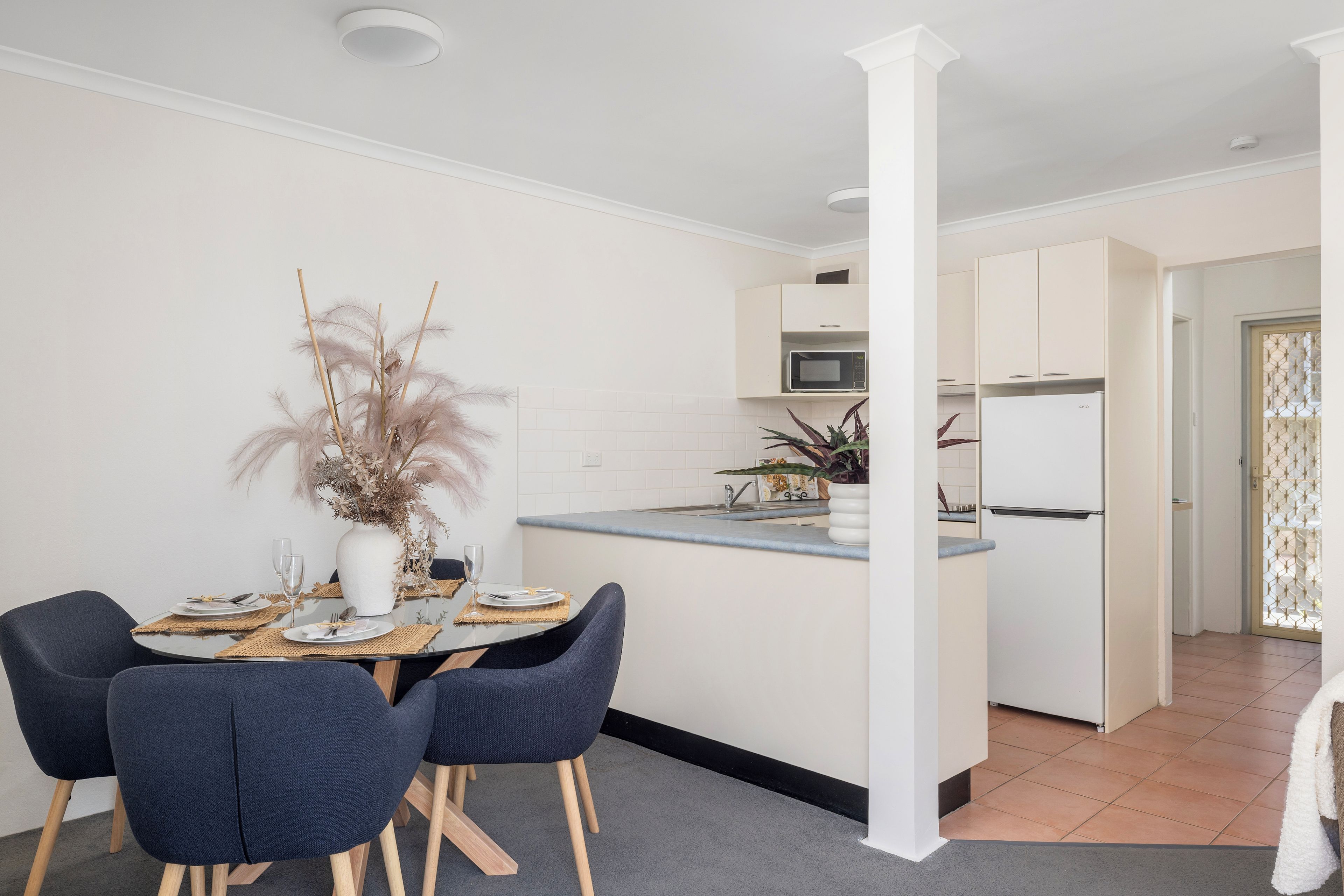 A modern kitchen with white cabinets, a built-in microwave, and a refrigerator.