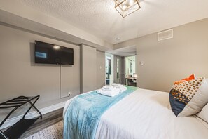 Une chambre d’hôtel avec un lit, un téléviseur fixé au mur, une chaise et un bureau avec un miroir.