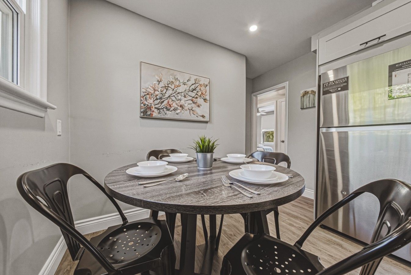 A dining area with a round table, chairs, and a potted plant.