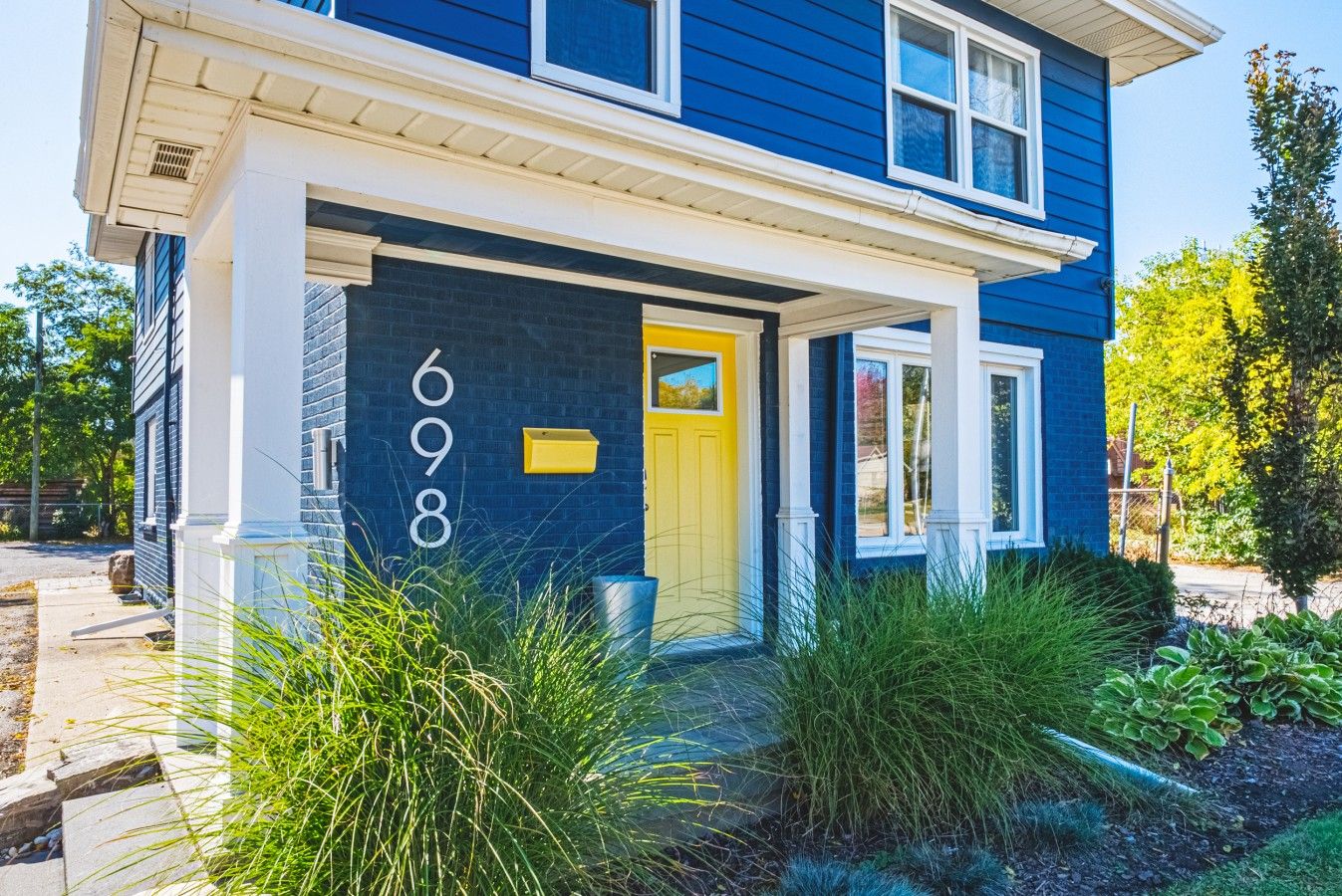 Une maison à deux étages, avec une façade bleue, une porte jaune et le numéro 698 peint sur le mur.