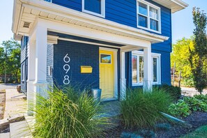 Une maison à deux étages, avec une façade bleue, une porte jaune et le numéro 698 peint sur le mur.