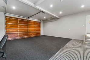 A garage with a wooden door, a black office chair, and a grey carpet. - View from the Top - lake & mountain views! (Taupo)