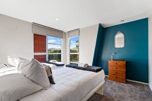 A bedroom with a bed, a dresser, a mirror, and a window with a view. - View from the Top - lake & mountain views! (Taupo)