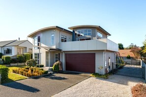 A two-story house with a garage, a covered driveway, and a landscaped front yard. - View from the Top - lake & mountain views! (Taupo)