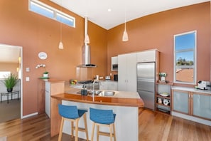 A modern kitchen with a central island, stainless steel appliances, and pendant lighting. - View from the Top - lake & mountain views! (Taupo)