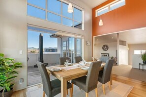 A dining area with a wooden table set for four, large windows, and a view of the outdoors. - View from the Top - lake & mountain views! (Taupo)