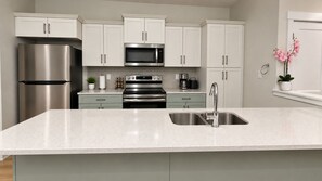 A modern kitchen with stainless steel appliances, white cabinetry, and a granite countertop. - Modern 3BR/2.5BA Home | Free Parking, WiFi, Full Kitchen, Laundry & Deck (Regina)