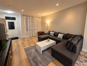 Ein modernes Wohnzimmer mit einer Eckcouch, einem weißen Couchtisch und einem kleinen Beistelltisch.