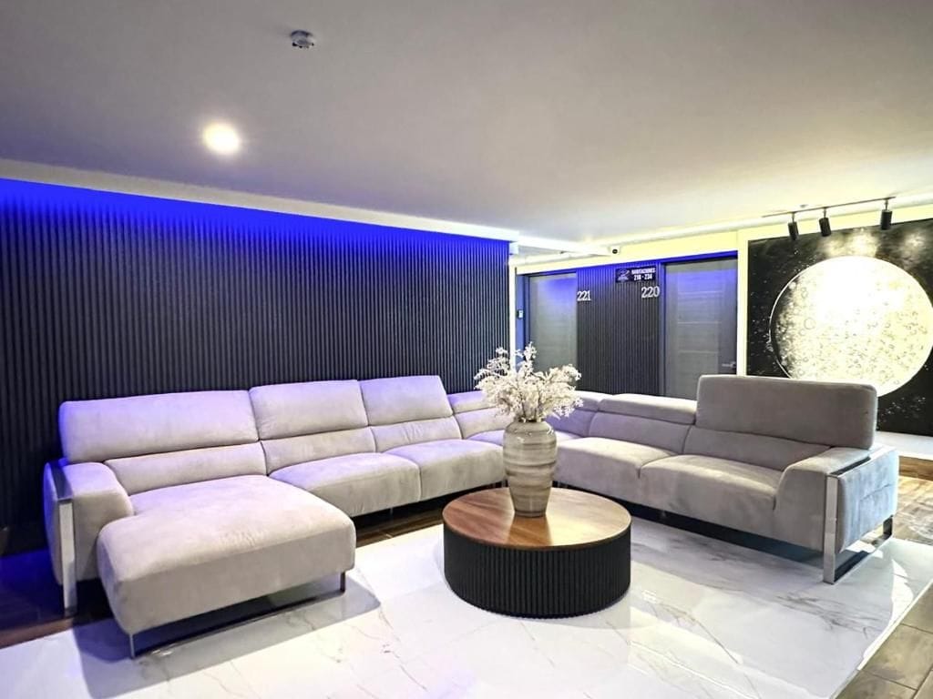 Una sala moderna con un sofá modular, una mesa de centro redonda y una obra de arte grande en la pared.