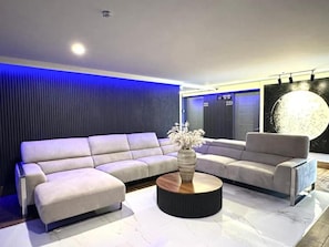 A modern living room with a sectional sofa, a round coffee table, and a large artwork on the wall. - Hotel Mission Space 360 (Cancún)