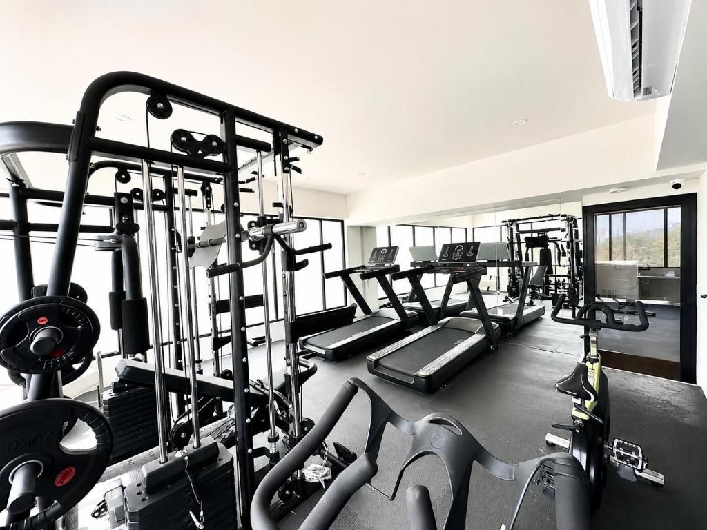 Un gimnasio con equipamiento de ejercicio, cintas de correr y estaciones de levantamiento de pesas.