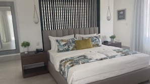 Un dormitori modern amb un llit, fallegueres, un mirall i una finestra amb cortines.