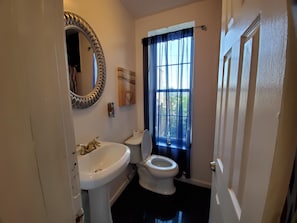 A bathroom with a white sink, toilet, and a mirror with a decorative frame. - Room-cozy Bedroom Sleep two Guest has Wi (Camden)