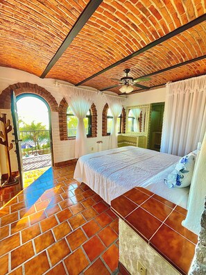 A room with a large bed, arched windows, and a view of the outdoors. - New Listing (San Juan Tecomatlan)