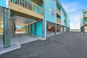 A two-story building with a covered parking area and a visible garage door. - Quaint Getaway With Pool and Beach Access (Gulf Shores)
