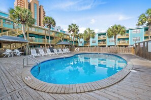 A swimming pool with lounge chairs, wooden deck, and a wooden fence. - Quaint Getaway With Pool and Beach Access (Gulf Shores)