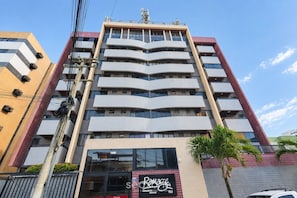 A multi-story building with a modern architectural design, featuring balconies on each floor and a ground-level entrance with signage. - Apt. w/ Sea View in Condo. w/ Pool Ere0406 (Maceió)