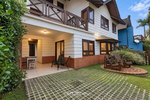 A two-story house with a balcony, a patio with outdoor furniture, and a well-maintained garden. - House in Condo. w/ Priv. BBQ Piw0003 (Imbituba)