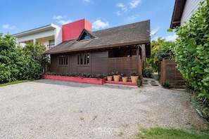 A modern house with a gravel driveway, a red planter with plants, and a wooden fence. - House in Condo. w/ Priv. BBQ Piw0005 (Imbituba)