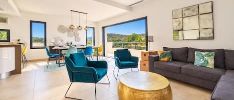 A spacious living area with a sofa, chairs, and a dining table.