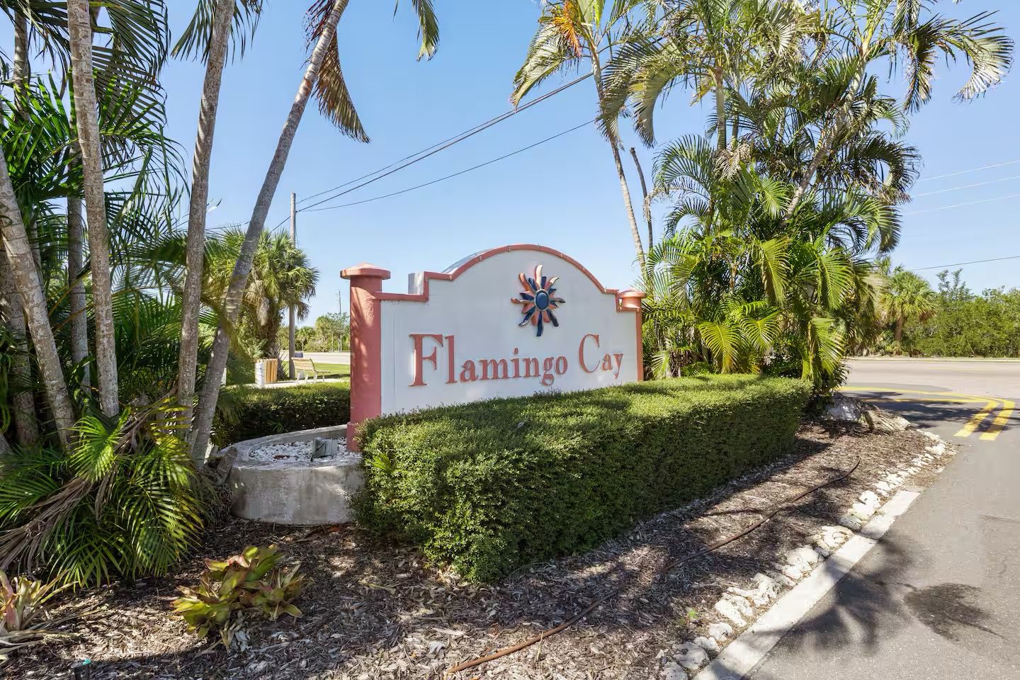 Un panneau indiquant l’accès à Flamingo Cay, avec une route dégagée et des palmiers en arrière-plan.