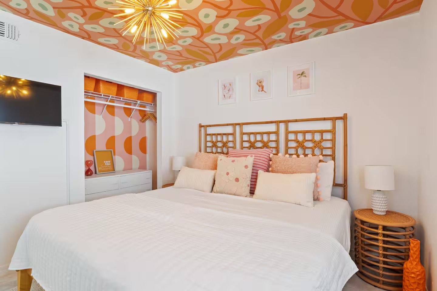 Une chambre avec un grand lit, un téléviseur fixé au mur et un plafond décoratif.
