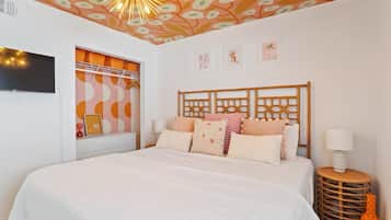 Une chambre avec un grand lit, un téléviseur fixé au mur et un plafond décoratif.