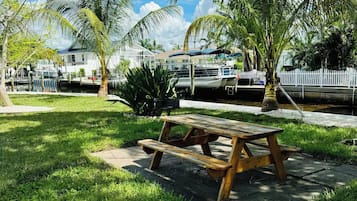 Een picknicktafel in een gazon met palmbomen en een boot in de verte.