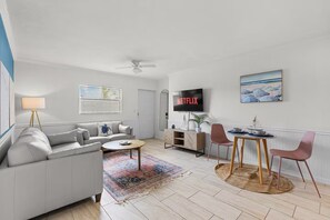 Un salon moderne comprenant un canapé, une table basse, un téléviseur et un coin repas avec des chaises et une table.