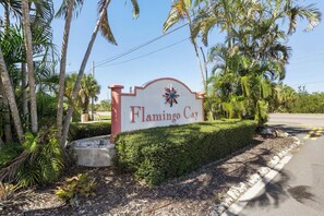 Un panneau indiquant l’accès à Flamingo Cay, avec une route dégagée et des palmiers.