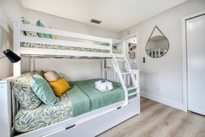 Ein Etagenbett mit einer Treppe, ein Schreibtisch, eine Lampe und ein Spiegel an der Wand.