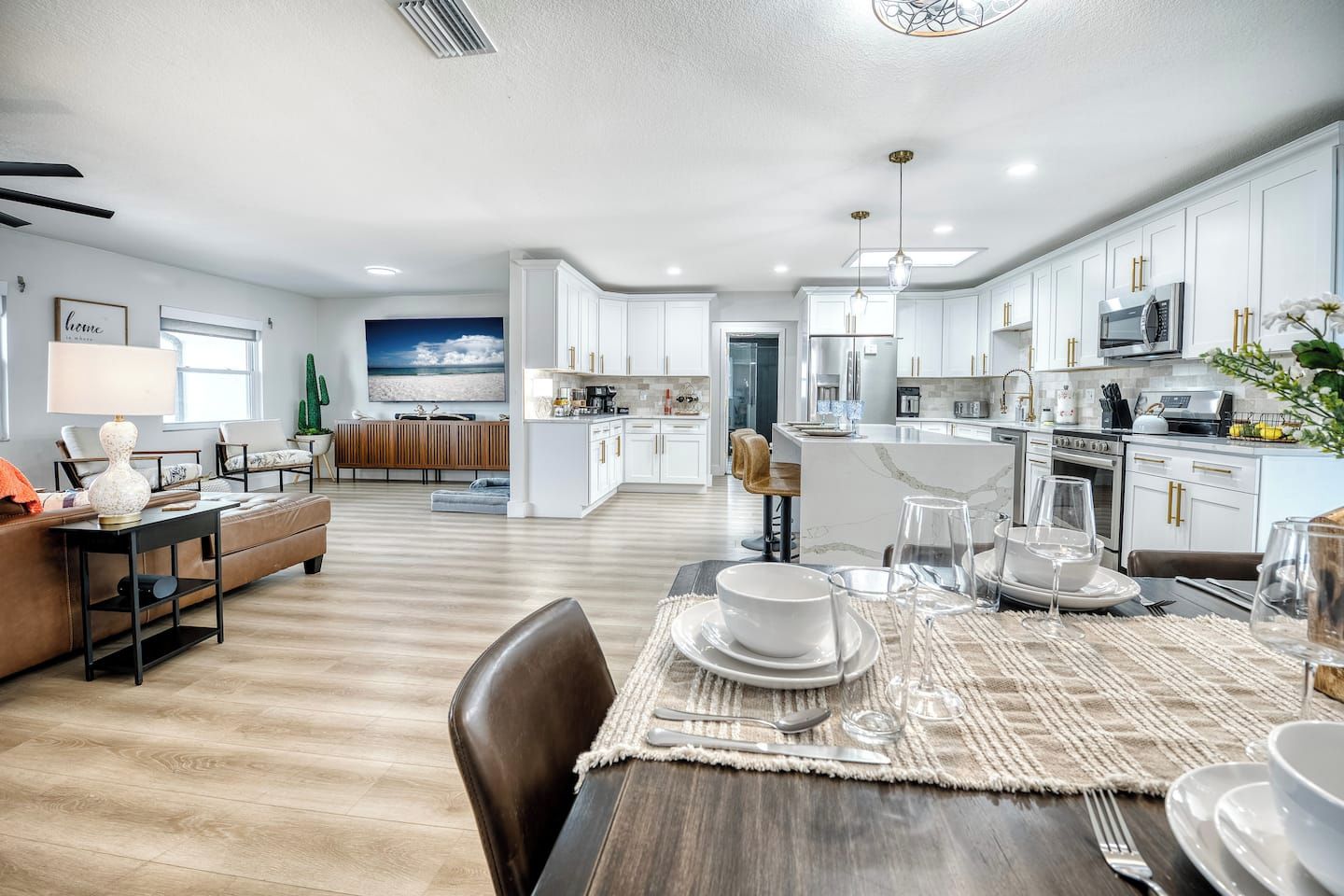 A modern kitchen with white cabinets, stainless steel appliances, and a dining area with a wooden table set for a meal.