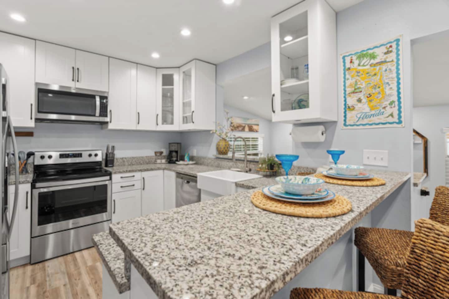 A modern kitchen with white cabinets, stainless steel appliances, granite countertops, and a central island with blue bowls.