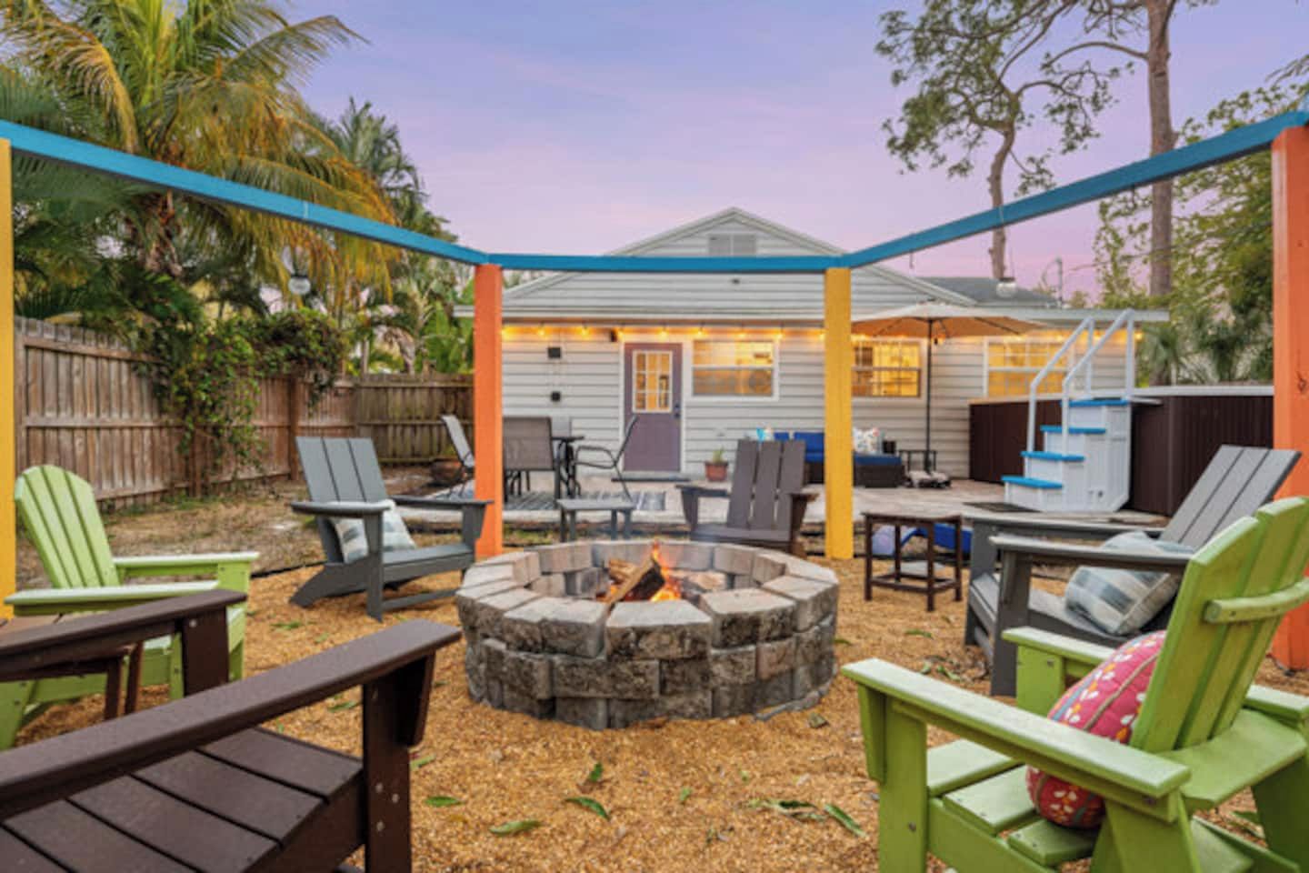 A covered outdoor patio with seating, a fire pit, and a staircase leading to an upper level.