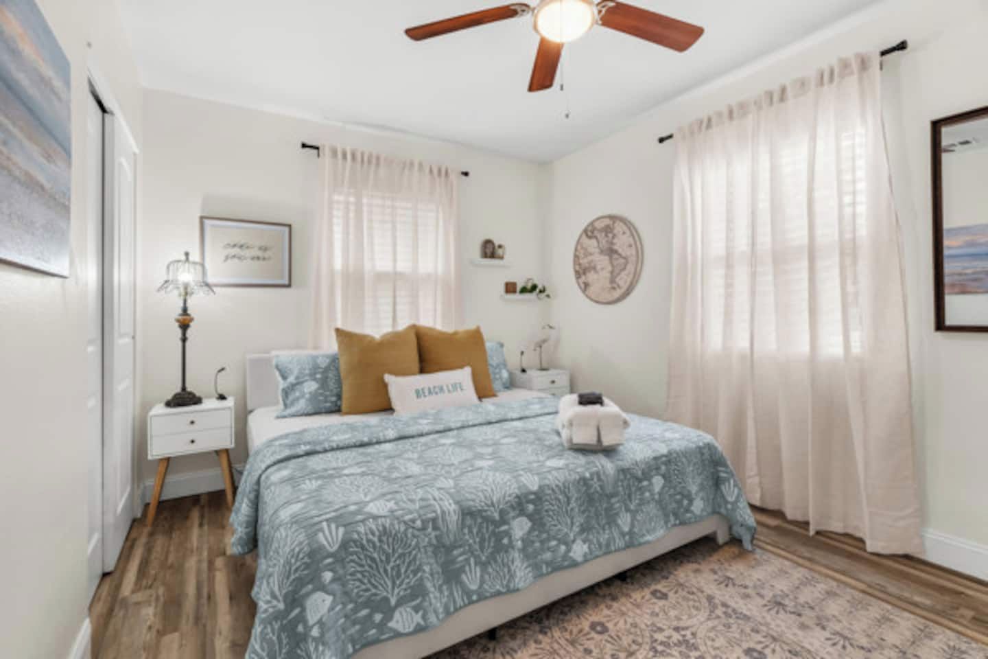 A bedroom with a bed, a nightstand, a lamp, a ceiling fan, and a rug.