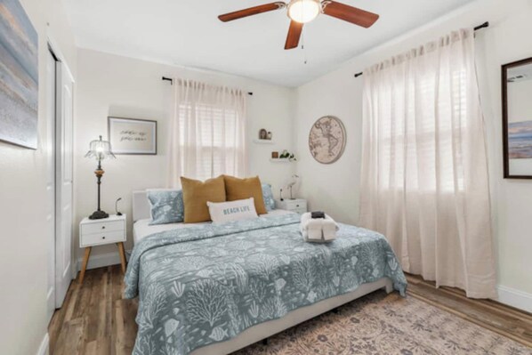 A bedroom with a bed, a nightstand, a lamp, a ceiling fan, and a rug.