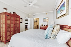 A bedroom with a large bed, a wardrobe, a ceiling fan, and a painting on the wall. - Beachfront Resort Condo With Pools, Spa, Club House and Pickleball Court (Gulf Shores)