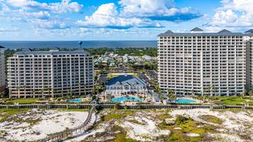 A resort with multiple high-rise buildings, a central pool area, and a beach in the foreground.