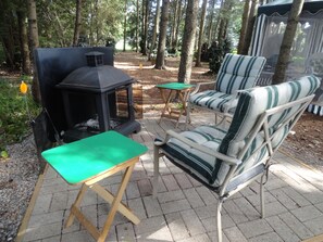 An outdoor seating area with a grill, a green table, and striped chairs. - Lovers Lane Getaway (Wellington North)