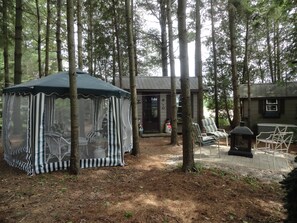 A forested area with a tent, a small building, and outdoor seating. - Lovers Lane Getaway (Wellington North)