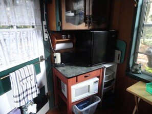 A compact kitchenette with a microwave, a small refrigerator, and a sink. - Lovers Lane Getaway (Wellington North)