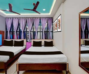 A hotel room with two beds, a ceiling fan, large windows with purple curtains, and framed artwork on the wall. - Classic Hotel Sunshine (Gop)