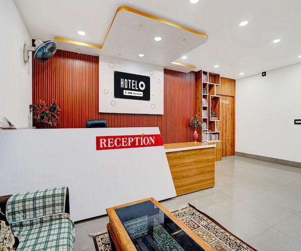 A hotel reception area with a reception desk, a sign indicating the hotel name, a bookshelf, and a conference room. - Classic Hotel Sunshine (Gop)