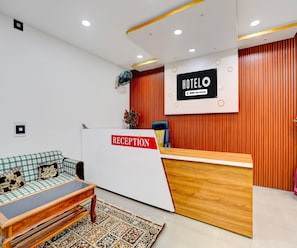 A hotel reception area with a reception desk, a sofa, and a patterned rug. - Classic Hotel Sunshine (Gop)