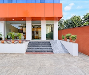 A modern building with a red and blue facade, a set of stairs leading to the entrance, and potted plants on the ground. - Classic Hotel Sunshine (Gop)