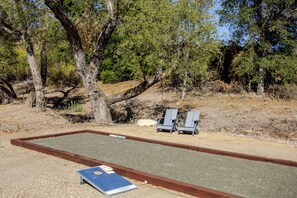 A billiards table with cue sticks and a chalkboard in a natural setting with trees. - Willow & Vine: 2 BD/2BA, BBQ, Bocce (Paso Robles)